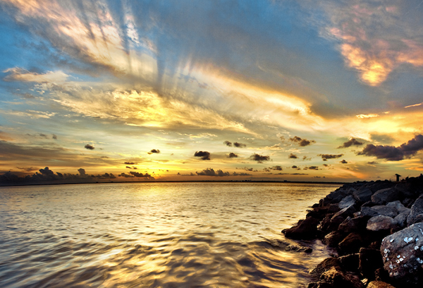 Dramatic pastel light sunset with sun rays in Santa Rosa Beach, Florida with Pensacola coastline coast cityscape skyline in panhandle and ocean